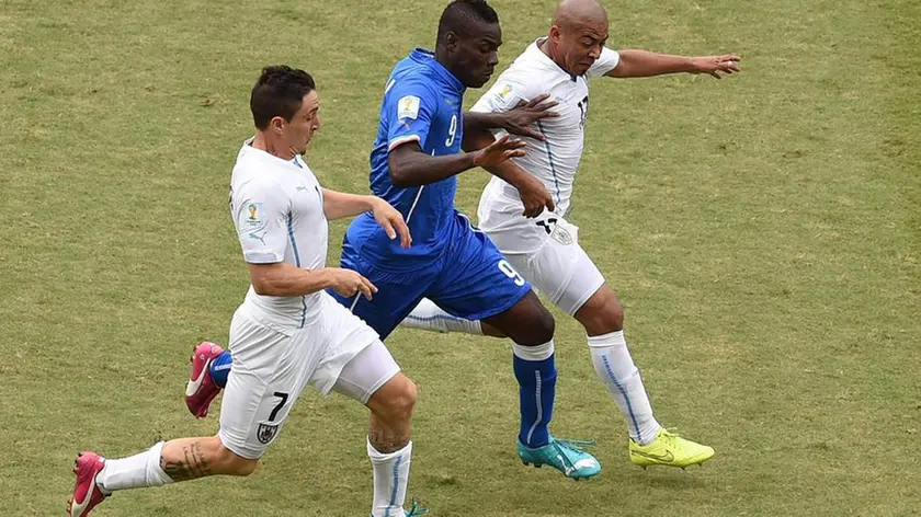 epa04277694 Mario Balotelli of Italy (C) in action against Cristian Rodriguez of Uruguay (L) and Egidio Arevalo of Uruguay during the FIFA World Cup 2014 group D preliminary round match between Italy and Uruguay at the Estadio Arena das Dunas in Natal, Brazil, 24 June 2014. (RESTRICTIONS APPLY: Editorial Use Only, not used in association with any commercial entity - Images must not be used in any form of alert service or push service of any kind including via mobile alert services, downloads to mobile devices or MMS messaging - Images must appear as still images and must not emulate match action video footage - No alteration is made to, and no text or image is superimposed over, any published image which: (a) intentionally obscures or removes a sponsor identification image; or (b) adds or overlays the commercial identification of any third party which is not officially associated with the FIFA World Cup) EPA/VASSIL DONEV EDITORIAL USE ONLY