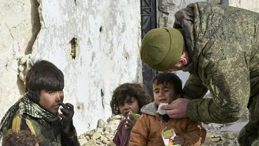 This undated handout photo released by the Russian Defense Ministry claims to show a Russian Military engineer distributing juice to local children in Aleppo, Syria.(Russian Defense Ministry Press Service photo via AP)