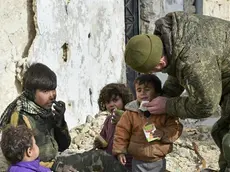 This undated handout photo released by the Russian Defense Ministry claims to show a Russian Military engineer distributing juice to local children in Aleppo, Syria.(Russian Defense Ministry Press Service photo via AP)