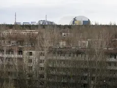 This photo taken Wednesday, March 23, 2016 shows abandoned apartment buildings in the town of Pripyat near Chernobyl, Ukraine, with a chimney, left, at the destroyed reactor and a gigantic arch-shape confinement to cover the remnants of the exploded reactor, in the back, at the Chernobyl nuclear power plant. Thirty years after the worlds worst nuclear accident, the Chernobyl nuclear power plant is surrounded by both a hushed desolation and clangorous activity, the sense of a ruined past and a difficult future. (ANSA/AP Photo/Efrem Lukatsky)