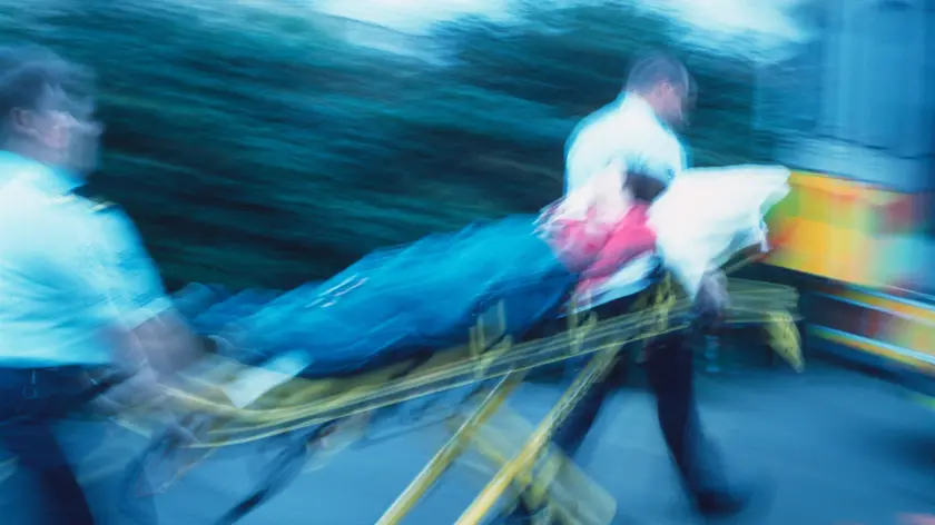 Ambulance treatment. Blurred image of paramedics rushing a patient on a trolley towards an ambulance.