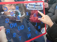 Un manifestante, affetto da SLA si esprime attraverso la lavagna, accompagnati con cartelloni e striscioni sotto il ministero delle Finanze per protestare contro la nuova norma che l'assistenza alle persone con disabilità e' da erogare conpatibilmente alle risorse di bilancio degli enti finanzianti. Roma 21 novembre 2012 ANSA/FABIO CAMPANA