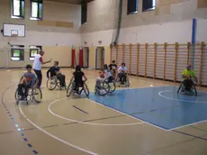 I ragazzi imparano a giocare basket sulla sedia a rotelle