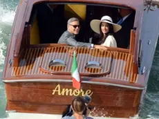 George Clooney, flanked by his wife Amal Alamuddin, sit on a water-taxi after leaving the city hall in Venice, Italy, Monday, Sept. 29, 2014. George Clooney married human rights lawyer Amal Alamuddin Saturday, the actor's representative said, out of sight of pursuing paparazzi and adoring crowds. (AP Photo/Luigi Costantini)