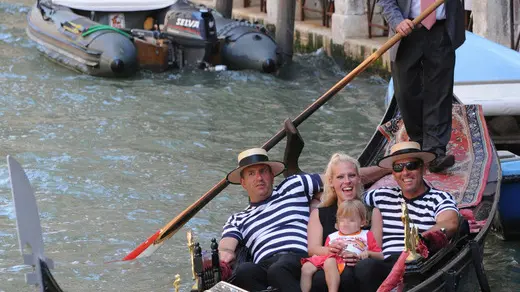 20090626 - VENEZIA - HUM - PRIMA GONDOLIERA IN LAGUNA, SI INCRINA DOMINIO UOMINI - Cade l'ultimo tabù a Venezia: da oggi anche una donna, dopo nove secoli di dominio maschile esclusivo, diventerà gondoliera. Giorgia Boscolo (nella foto di oggi 26 giugno 2009 tra due colleghi mentre il padre Dante, anche lui gondoliere, voga maldestramente per gioco), 23 anni, sposata e madre di due bambini, e' la prima esponente del gentil sesso ad aver superato l'esame di ammissione, entrando di diritto tra i frequentanti della scuola da sostituto gondoliere, dalla quale escono gli unici 'taxisti a remi' riconosciuti dall'Ente Gondola. In attesa di concludere il tirocinio, come riporta oggi il Gazzettino, Giorgia potrà traghettare i clienti, vogando a prua, come una sorta di 'secondo pilota'. ANSA/ANDREA MEROLA/GID