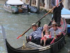 20090626 - VENEZIA - HUM - PRIMA GONDOLIERA IN LAGUNA, SI INCRINA DOMINIO UOMINI - Cade l'ultimo tabù a Venezia: da oggi anche una donna, dopo nove secoli di dominio maschile esclusivo, diventerà gondoliera. Giorgia Boscolo (nella foto di oggi 26 giugno 2009 tra due colleghi mentre il padre Dante, anche lui gondoliere, voga maldestramente per gioco), 23 anni, sposata e madre di due bambini, e' la prima esponente del gentil sesso ad aver superato l'esame di ammissione, entrando di diritto tra i frequentanti della scuola da sostituto gondoliere, dalla quale escono gli unici 'taxisti a remi' riconosciuti dall'Ente Gondola. In attesa di concludere il tirocinio, come riporta oggi il Gazzettino, Giorgia potrà traghettare i clienti, vogando a prua, come una sorta di 'secondo pilota'. ANSA/ANDREA MEROLA/GID