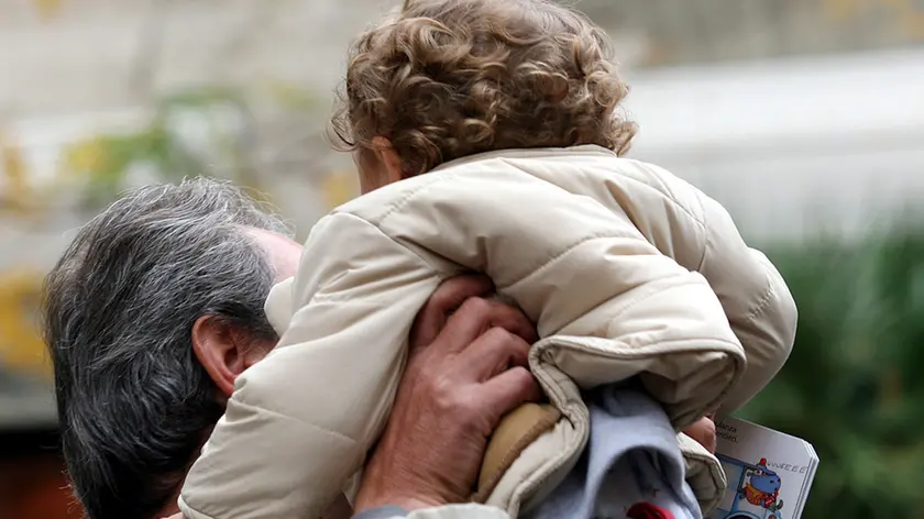 Un padre prende in braccio il suo bambino a Pontedera, in una foto d'archivio. ANSA / FRANCO SILVI