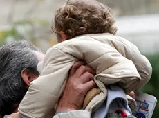 Un padre prende in braccio il suo bambino a Pontedera, in una foto d'archivio. ANSA / FRANCO SILVI