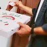 Un portapizze consegna una pizza per asporto a un cliente (foto Archivio)