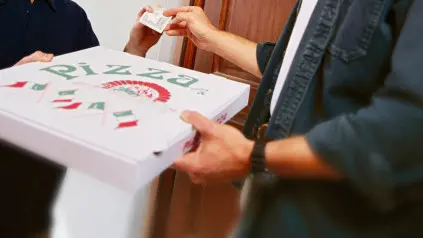Un portapizze consegna una pizza per asporto a un cliente (foto Archivio)