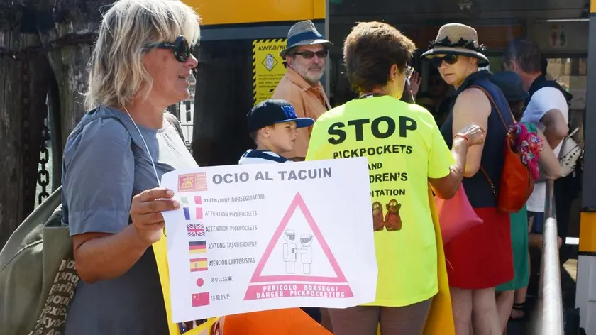 Una attivista dei Cittadini non distratti ad un imbarcadero con i cartelli contro le borseggiatrici