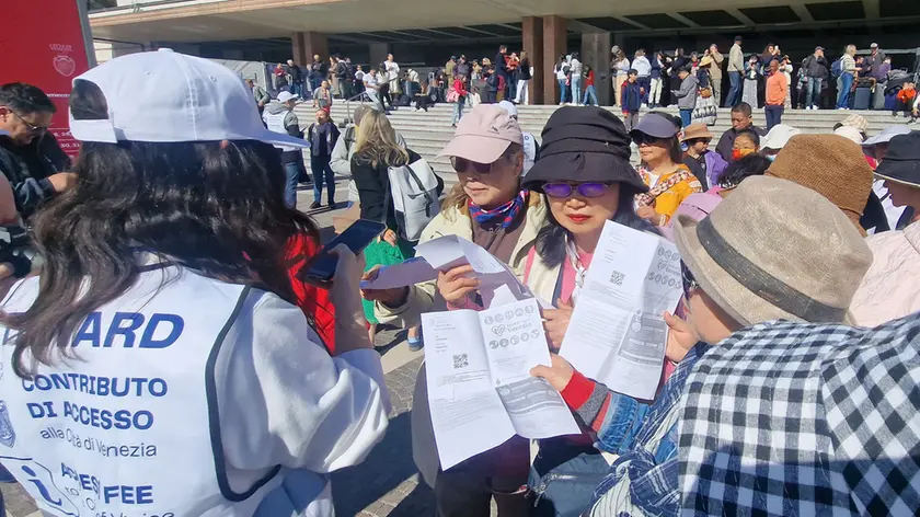 Alcuni turisti pendolari mentre mostrano la ricevuta di pagamento del contributo di accesso