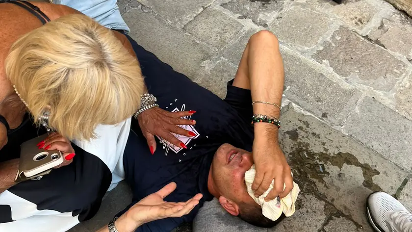 Il tabaccaio Cristian Tosi a terra dopo essere stato preso a pugni e calci