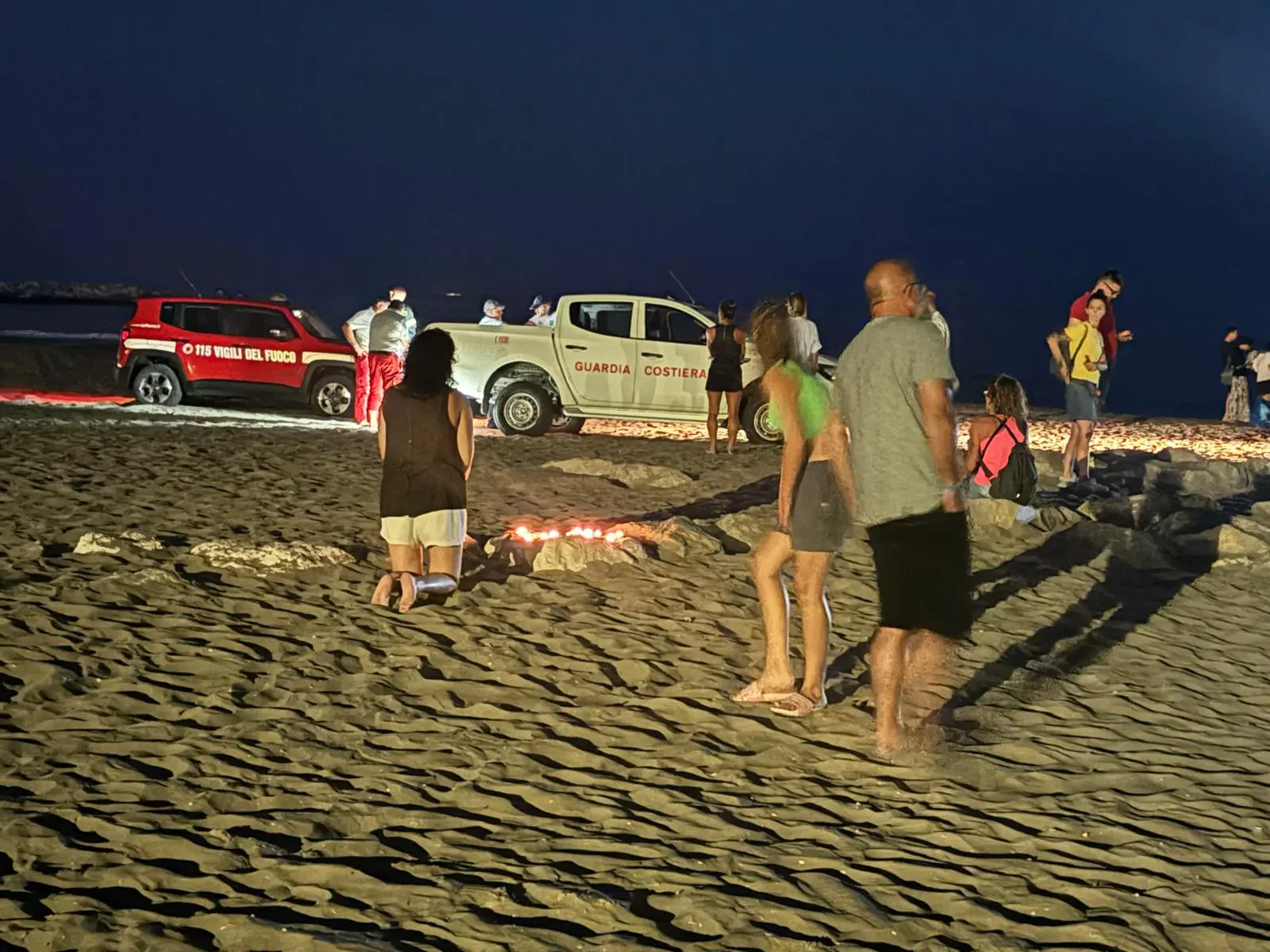 Una donna prega in spiaggia dove il bambino è sparito tra le onde