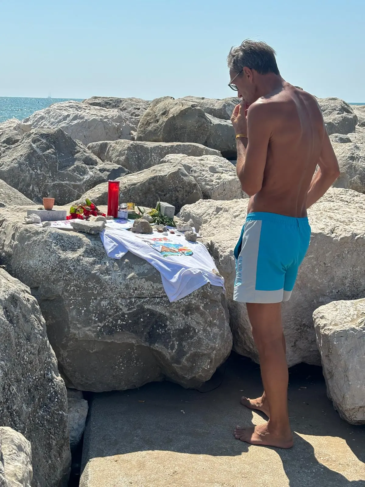 Un bagnante nel punto in cui è stato allestito un piccolo altare in ricordo di Carlo Panizzo