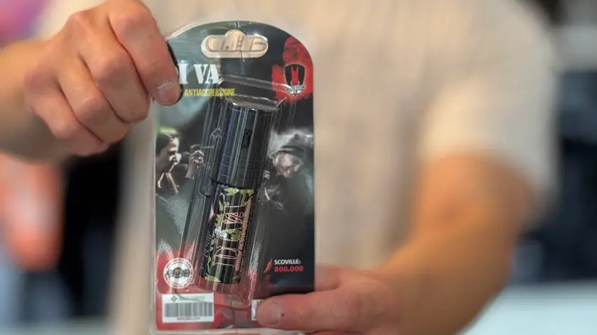 Un commerciante che mostra lo spry al peperoncino in vendita