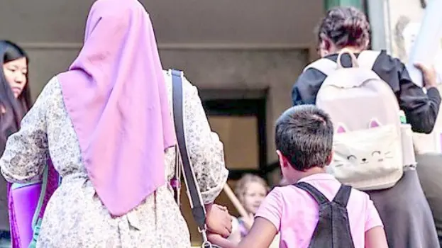 Una mamma musulmana che accompagna la propria figlia a scuola