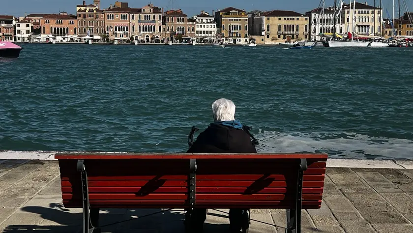 Un’anziana seduta su una panchina alla Giudecca, mentre guarda l’orizzonte: gli over 65 in centro storico sono in continua crescita