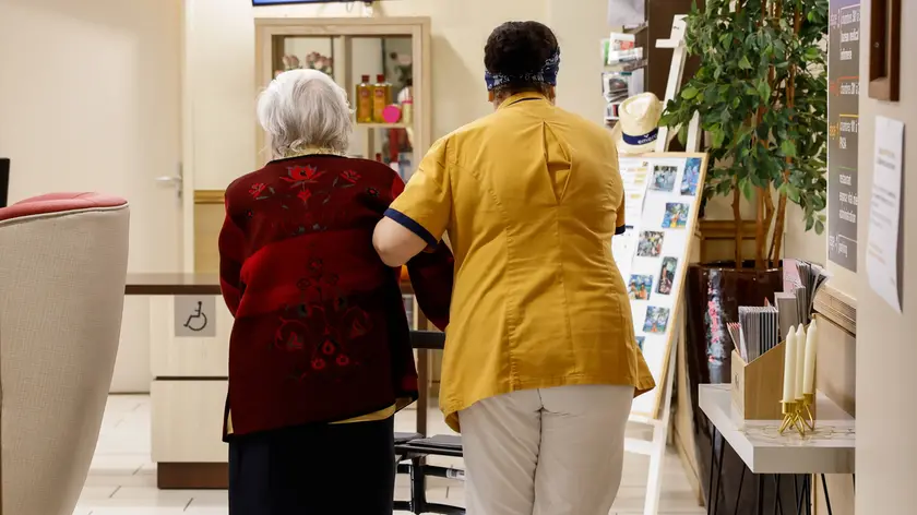 Un’anziana aiutata da un’operatrice socio sanitaria in casa di riposo