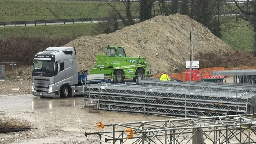 I tir portano via i macchinari dal cantiere della bretella (Foto Porcile)