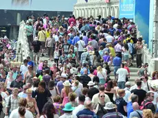 La classica immagine del ponte della Paglia intasato dai turisti. In alto, i lancioni che portano in giro in turisti in Bacino San Marco