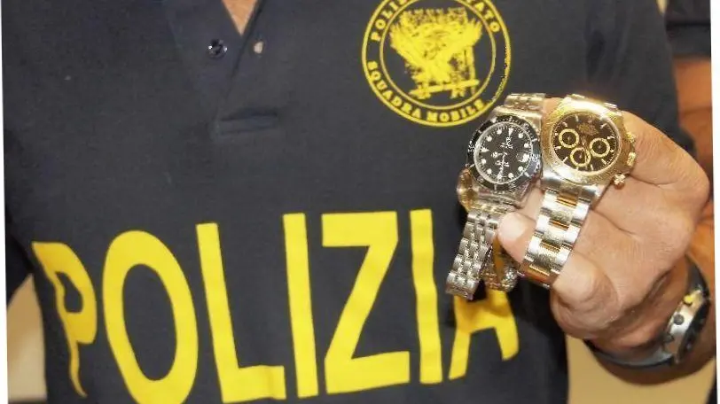 In una foto d'archivio un poliziotto mostra due Rolex recuperati.