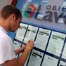 Un giovane annota un annuncio di offerta di lavoro presso la bacheca di un'agenzia interinale