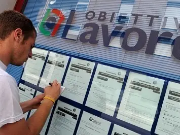 Un giovane annota un annuncio di offerta di lavoro presso la bacheca di un'agenzia interinale