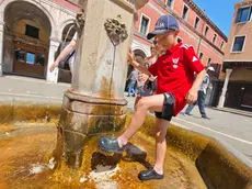 Un bambino trova refrigerio in una fontana