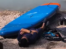Il turista sdraiato in riva al lago dopo aver solcato le acque con il sup