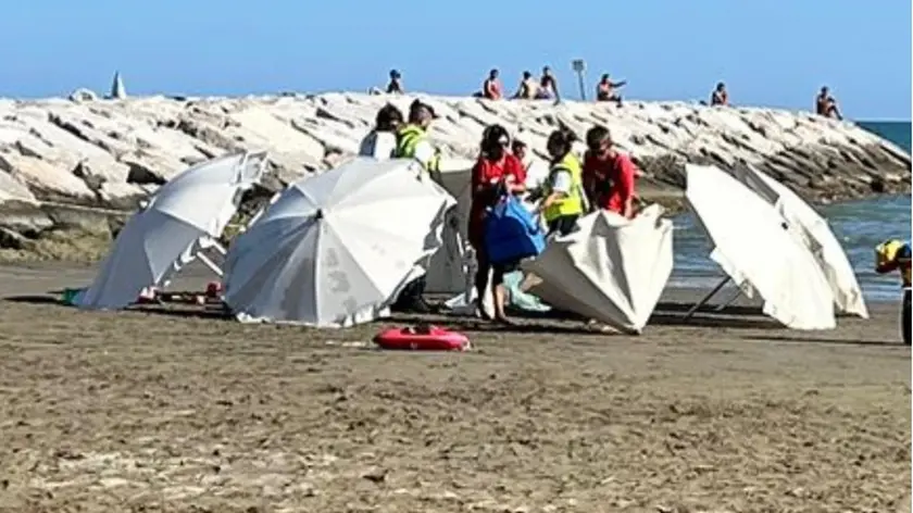 Una persona morta in spiaggia, i soccorritori attendono il carro funebre