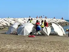 Una persona morta in spiaggia, i soccorritori attendono il carro funebre