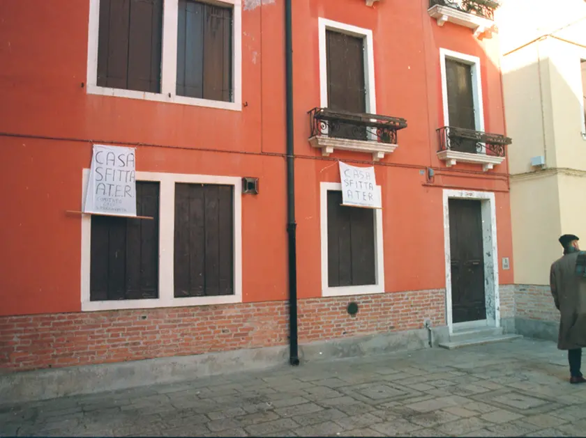 Una casa Ater sfitta e un cartello di protesta