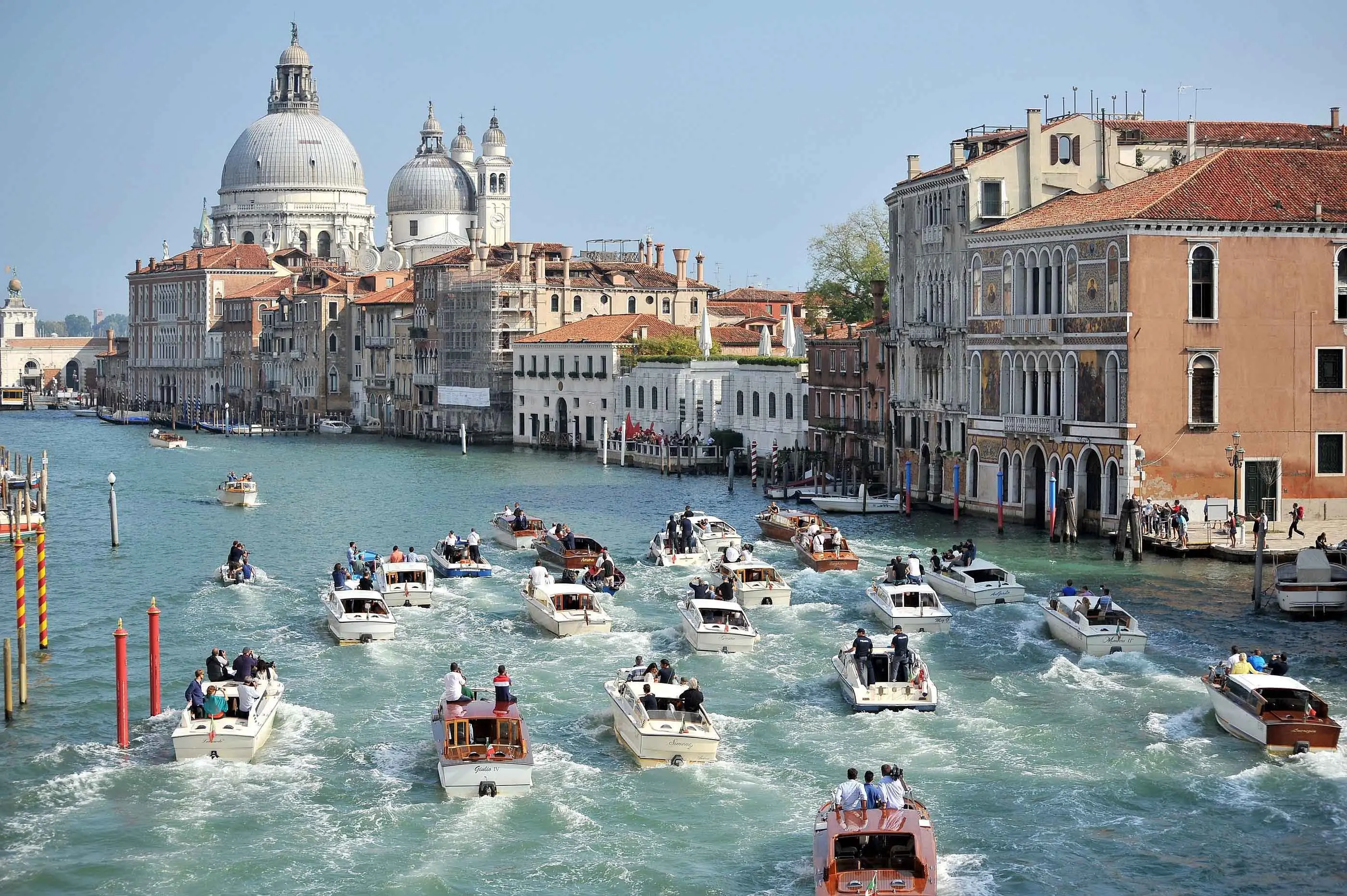 The boat carrying George Clooney and his wife Amal Alamuddin, is surrounded by media and security boats as they cruise the Grand Canal after leaving the Aman luxury Hotel in Venice, Italy, Sunday, Sept. 28, 2014. George Clooney married human rights lawyer Amal Alamuddin Saturday, the actor's representative said, out of sight of pursuing paparazzi and adoring crowds. (AP Photo/Luigi Costantini)