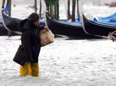 20081201 - VENEZIA - WEA - MALTEMPO: ALTRO GIORNO DIFFICILE, ACQUA ALTA RECORD A VENEZIA - Turisti camminano in piazza San Marco a Venezia, questa mattina 1 dicembre 2008, dove l'acqua alta raggiunge livelli da record . Nel capoluogo lagunare, piazza San Marco coperta da 80 cm d'acqua, mentre il centro maree ha fatto una previsione di acqua alta per le 12 di un metro e 60 centimetri: un evento in cui tutta la citta' finisce allagata. ..ANDREA MEROLA /ANSA /KLD