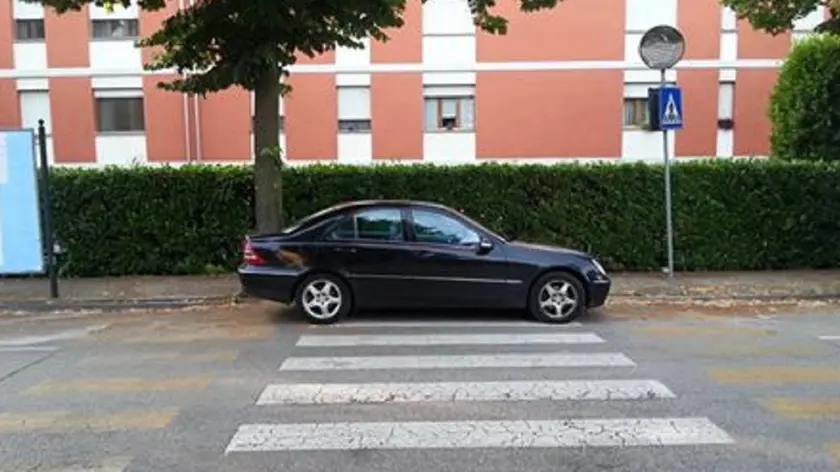 Auto posteggiata su strisce pedonali in rilievo. Tutti i posti attorno sono liberi