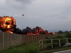 L'impressionante immagine con la scia di fuoco lasciata dall'aereo dopo lo schianto a terra e il pilota lanciatosi con il paracadute prima dell'impatto