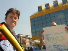 L'operaia Nicoletta Zago come lavavetri ad un incrocio di Mestre, mentre un suo compagno di lavoro mostra agli automobilisti un cartello di protesta, stamattina, 14 luglio 2011. La singolare protesta degli operai della Vinyls di Marghera dopo il fallimento delle trattative per il futuro dell'azienda chimica e il conseguente blocco degli stipendi. Hanno lavato i vetri delle auto, stamani, ad un incrocio, davanti alla sede di Mestre della Provincia di Venezia, i lavoratori della Vinyls di Marghera. E' stata per gli operai una diversa forma di protesta per rimettereal centro dell' attenzione la situazione occupazionale dello stabilimento veneziano. ANSA/ANDREA MEROLA