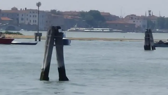 A sinistra nella foto, la gondola capovolta nel tratto di laguna davanti alla fermata Actv dei Bacini