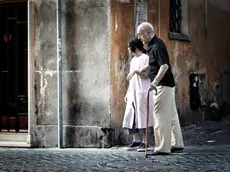 Una badante straniera accompagna un anziano signore per le vie del centro di Roma,in una foto del 2 settembre 2009. . I costi dell'assistenza ai disabili pesano sempre di piu' sulle loro famiglie. E in tempo di crisi i parenti studiano strategie di ''arrangiamento organizzato'' che passano anche attraverso il volontariato, prima di rivolgersi al settore privato o alle badanti. E' quanto emerge dal 44mo.Rapporto annuale del Censis sulla situazione sociale del Paese, che ha stimato in oltre 56mila euro, il costo di un malato di Alzheimer all'anno. Cifra che scende a 11.250 euro/anno per un paziente con artrite reumatoide e circa 15mila euro per i malati di insufficienza renale cronica in dialisi. ANSA/ GUIDO MONTANI