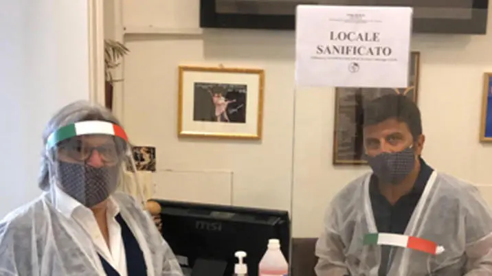 Due parrucchieri indossano mascherine sanitarie e visiere ne loro esercizio a Palermo, 8 maggio 2020: Affilano le forbici gli oltre ottomila barbieri, parrucchieri e titolari di centri benessere siciliani che si preparano all’apertura delle botteghe al massimo entro il prossimo 18 maggio. Solo a Catania si parla di oltre 1.800 attività, 1.700 a Palermo e 1.200 a Messina. Nelle ultime settimane, i maestri del taglio hanno rivoluzionato gli spazi dove lavorano, regolando la distanza tra le poltrone, inserendo barriere in plexiglass, armandosi di tutto punto di visiere, mascherine, camici e guanti in lattice. ANSA