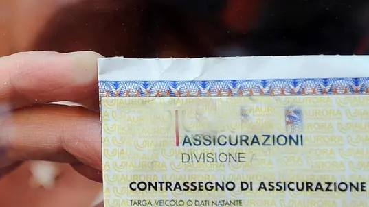 Una ragazza sistema il contrassegno dell'assicurazione sul parabrezza dell'auto, in un'immagine d'archivio. I premi rc auto sono in Italia in media più elevati e crescono più velocemente rispetto a quelli dei principali paesi europei. E' quanto emerge da un'indagine Antitrust sul settore. Il premio medio è più del doppio di quelli di Francia e Portogallo, supera quello tedesco dell'80% circa e quello olandese di quasi il 70%. ANSA/CLAUDIO ONORATI