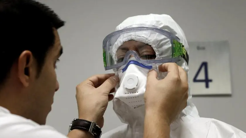 epa04444834 An auxiliary nurse gets dressed, aided by an instructor, in a special protection suit to be worn when dealing with cases of Ebola, during a clinical drill at La Fe Hospital in Valencia, eastern Spain, 13 October 2014. EPA/JUAN CARLOS CARDENAS