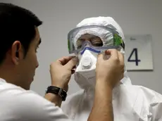 epa04444834 An auxiliary nurse gets dressed, aided by an instructor, in a special protection suit to be worn when dealing with cases of Ebola, during a clinical drill at La Fe Hospital in Valencia, eastern Spain, 13 October 2014. EPA/JUAN CARLOS CARDENAS