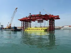 Una immagine dell'installazione della prima paratoia del Mose, Venezia, 14 giugno 2013. Posizionata ieri nel canale di Lido-Treporti, sono iniziate le operazioni di varo: la paratoia è stata lentamente calata in acqua per essere installata nel "cassone" di alloggiamento sott'acqua tramite uno speciale "mezzo di varo". ANSA / US CONSORZIO VENEZIA NUOVA ++NO SALES EDITORIAL USE ONLY++