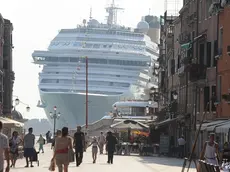 La prua di una grande nave da crociera torreggia all'ingresso di via Garibaldi, nel sestiere di Castello, a nord del centro storico di Venezia, 8 luglio 2011. Così appare ai passanti mentre la meganave è impegnata a curvare verso il Lido, in direzione della bocca di porto di San Nicolò ed il mare aperto. Italia Nostra ha denunciato la pericolosità per Venezia di questo genere di traffico marittimo. .ANSA/ANDREA MEROLA