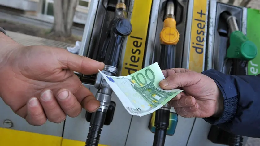 Un benzinaio alla pompa di benzina, riceve un biglietto da 100 euro per il pagamento del carburante da un cliente, 12 marzo 2012 a Pisa. ANSA/FRANCO SILVI