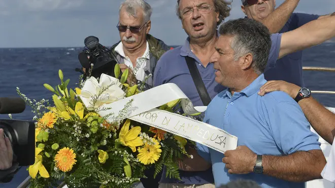 Fishing boat captain Calosero Spalma, right, throws a wreath, with writing on a ribbon written in Italian "Fishermen of Lampedusa", into the sea to pay tribute to the victims of Thursday's migrant shipwreck off the coast of the southern Italian island of Lampedusa, Saturday, Oct. 5, 2013. A 20-meter boat packed with migrants sank Thursday when the ship capsized after they started a fire to attract attention. Just 155 people survived, 111 bodies have been recovered and more than 200 are still missing. (AP Photo/str)