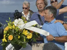 Fishing boat captain Calosero Spalma, right, throws a wreath, with writing on a ribbon written in Italian "Fishermen of Lampedusa", into the sea to pay tribute to the victims of Thursday's migrant shipwreck off the coast of the southern Italian island of Lampedusa, Saturday, Oct. 5, 2013. A 20-meter boat packed with migrants sank Thursday when the ship capsized after they started a fire to attract attention. Just 155 people survived, 111 bodies have been recovered and more than 200 are still missing. (AP Photo/str)