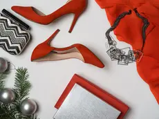 Top view to New Year and Christmas party outfit composition red shoes accessories jewelry makeup clutch hourglass fir tree with balls white background. Party date night conception. Flat lay, copy space